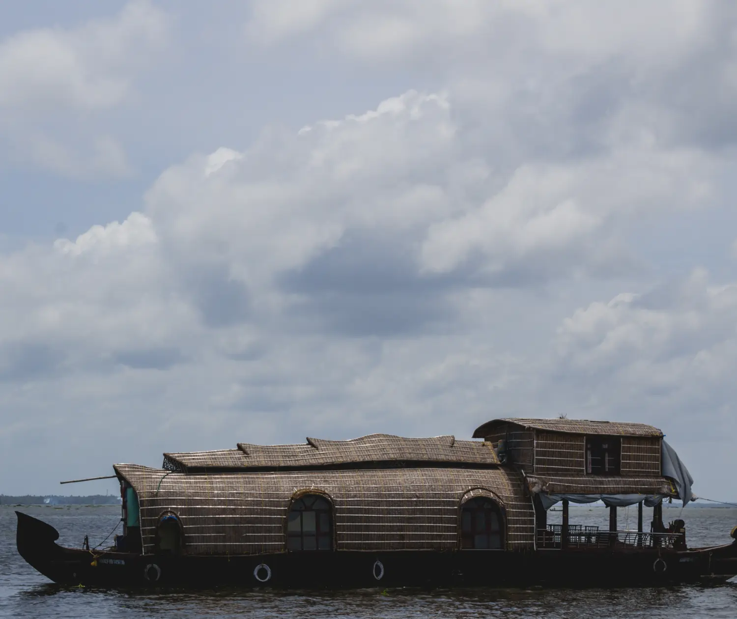 Kerala Boat House floating on scenic backwaters under cloudy sky