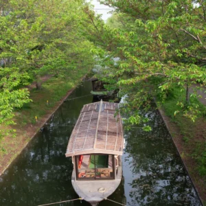 Traditional houseboat on the Alleppey houseboat route in Kerala backwaters surrounded by lush greenery.